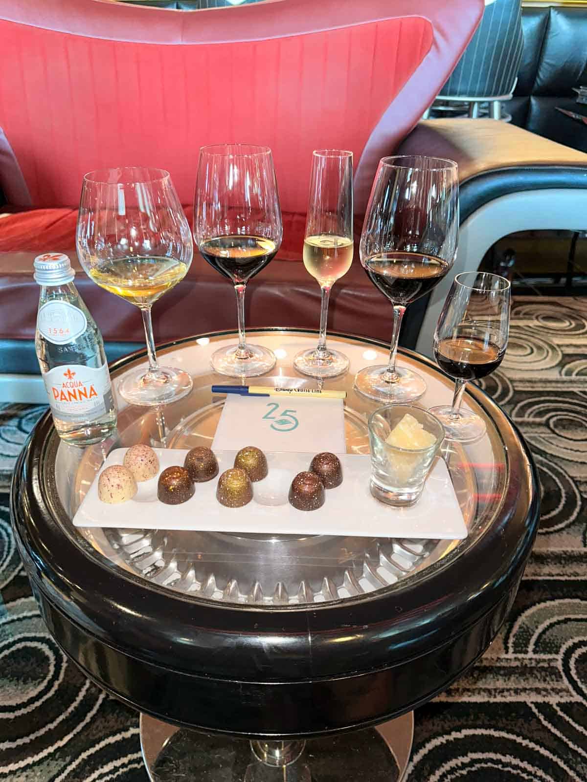 A small round table with wine glasses lined up and chocolates in front of them.