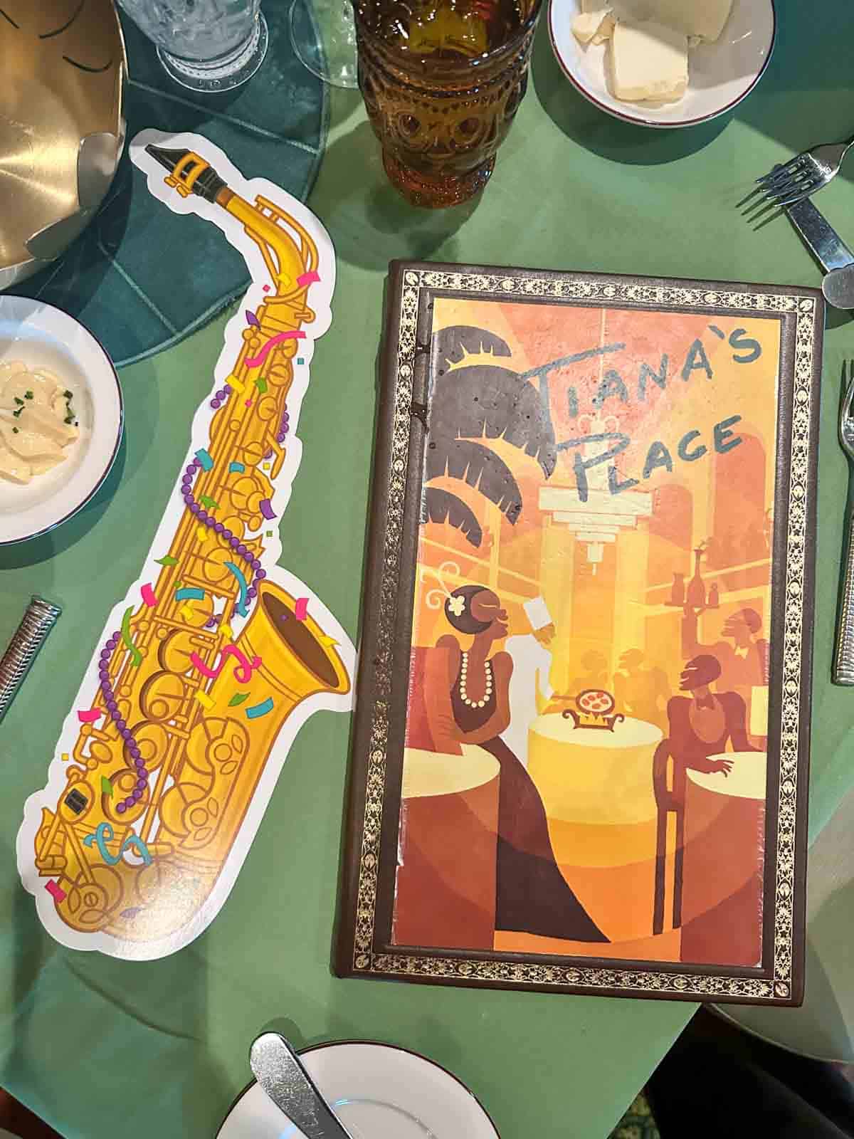 A green tablecloth with a bright yellow and orange menu next to a cut out of a saxaphone.
