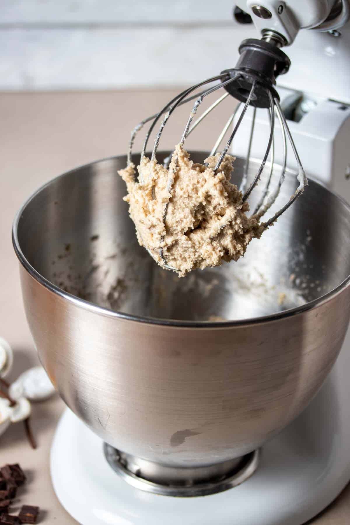 A stand mixer with a which extension that has a butter sugar whipped mixture on it.