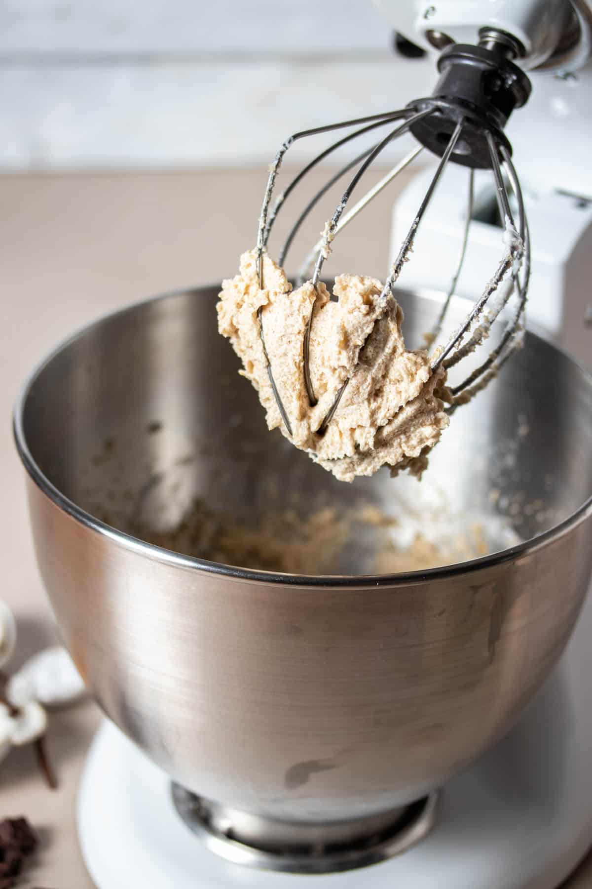A whisk mixer extension on a mixer stand with cookie dough on it.