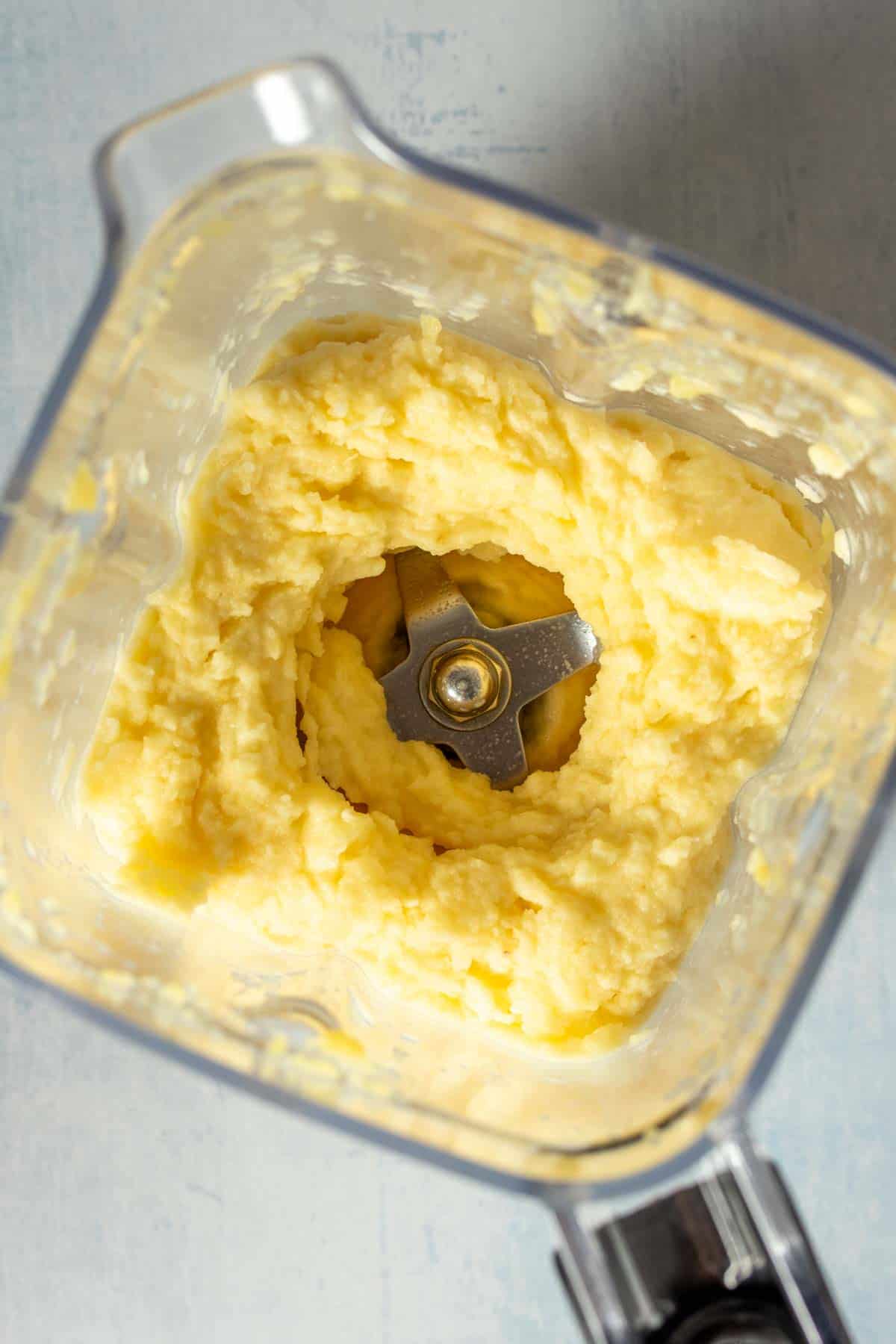 Top view looking into a blender with creamy blended pineapple.