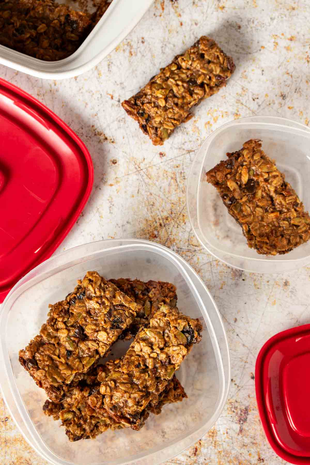 Top view of plastic containers and red lids and breakfast bars in the containers.