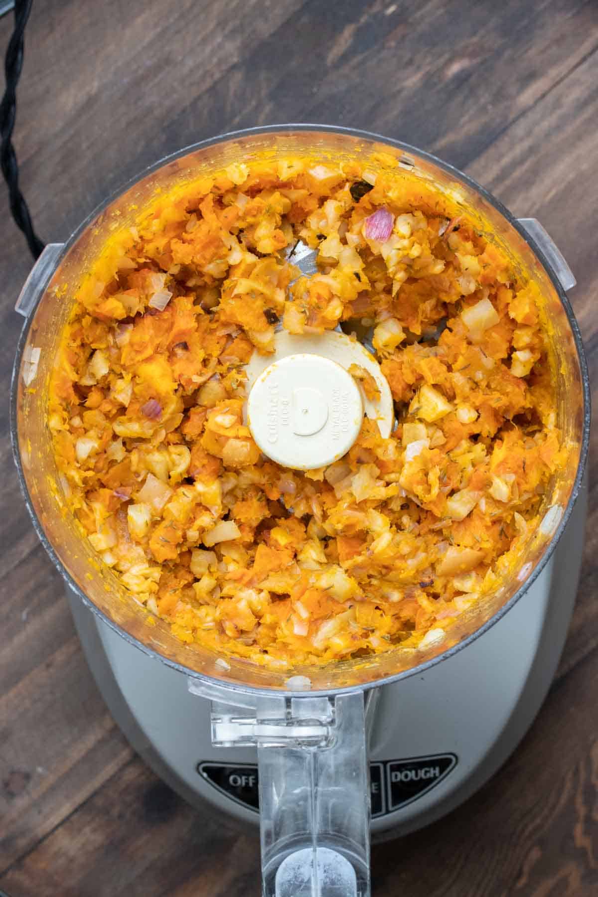 Top view of a food processor with pulsed butternut squash inside.