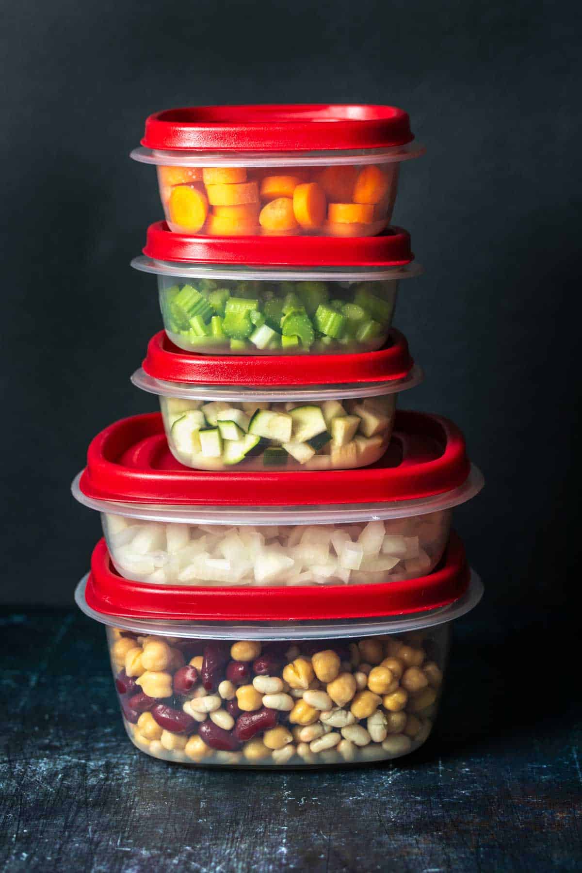 Two large and three small plastic containers with red lids stacked up.