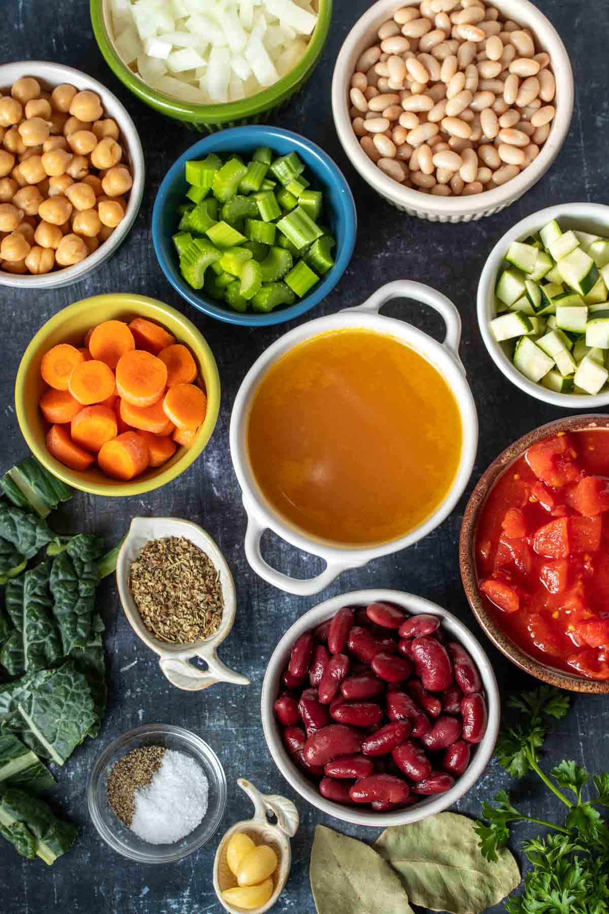 Top view of different color and size bowls with ingredients to make a vegetable bean soup.