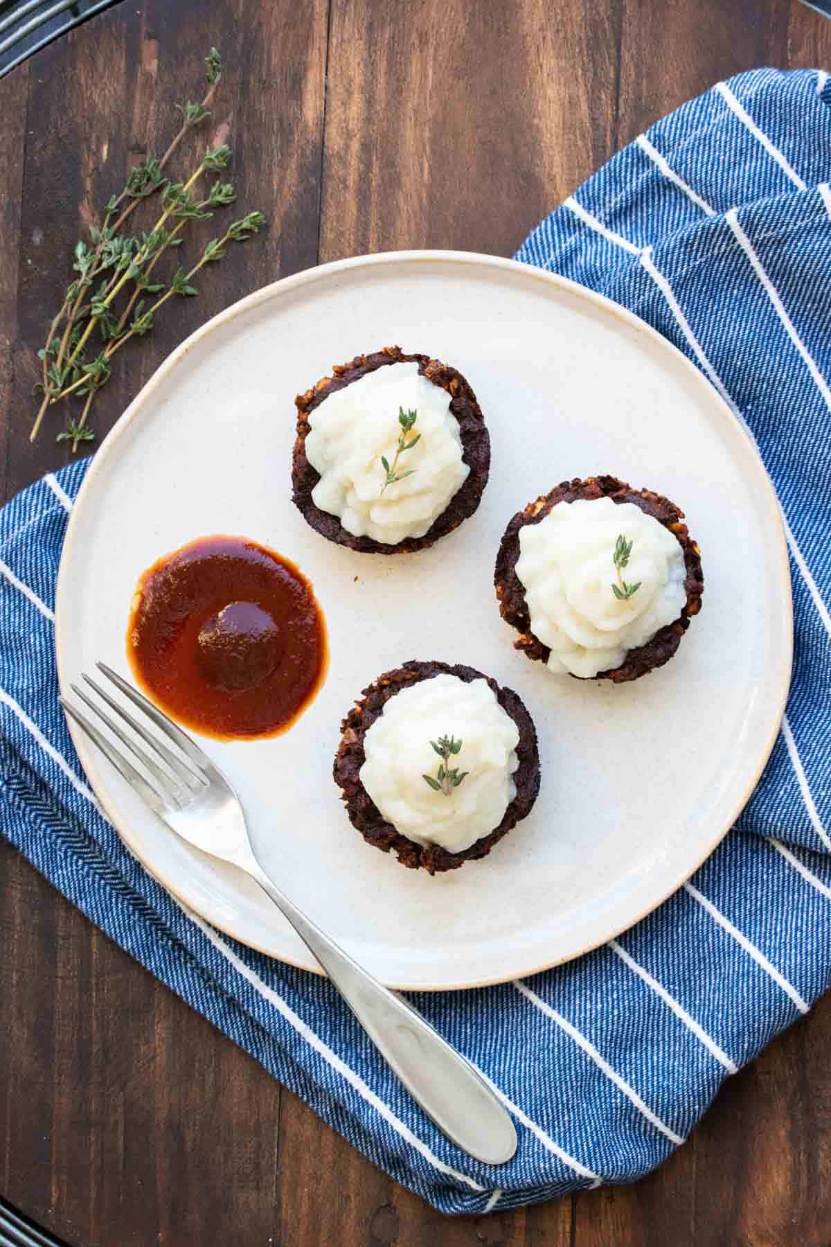 Top view of lentil meat loaf made into muffin cups topped with mashed potatoes on a plate.