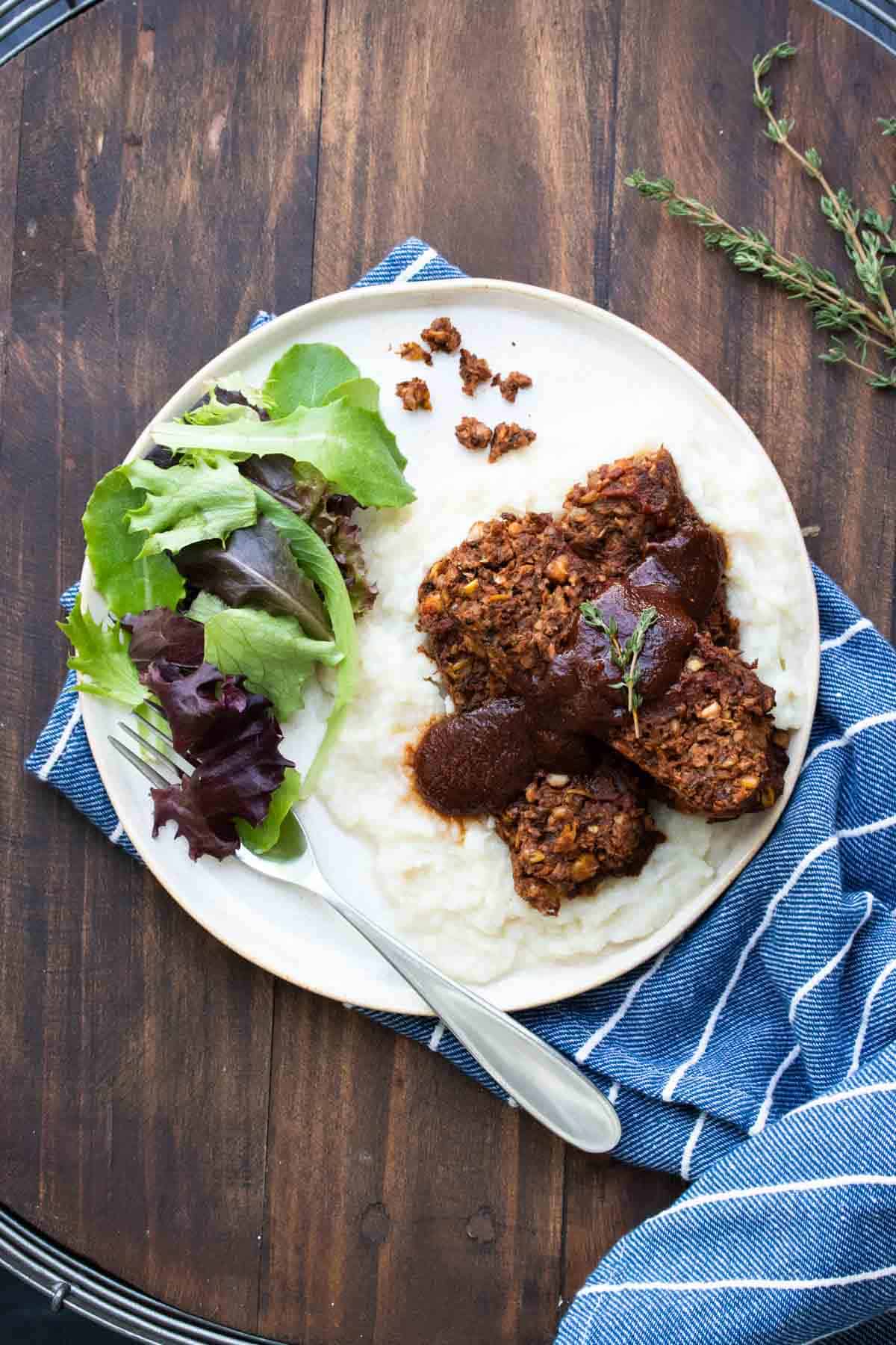 A fork getting a bite of salad from a plate with lentil meatloaf on it.