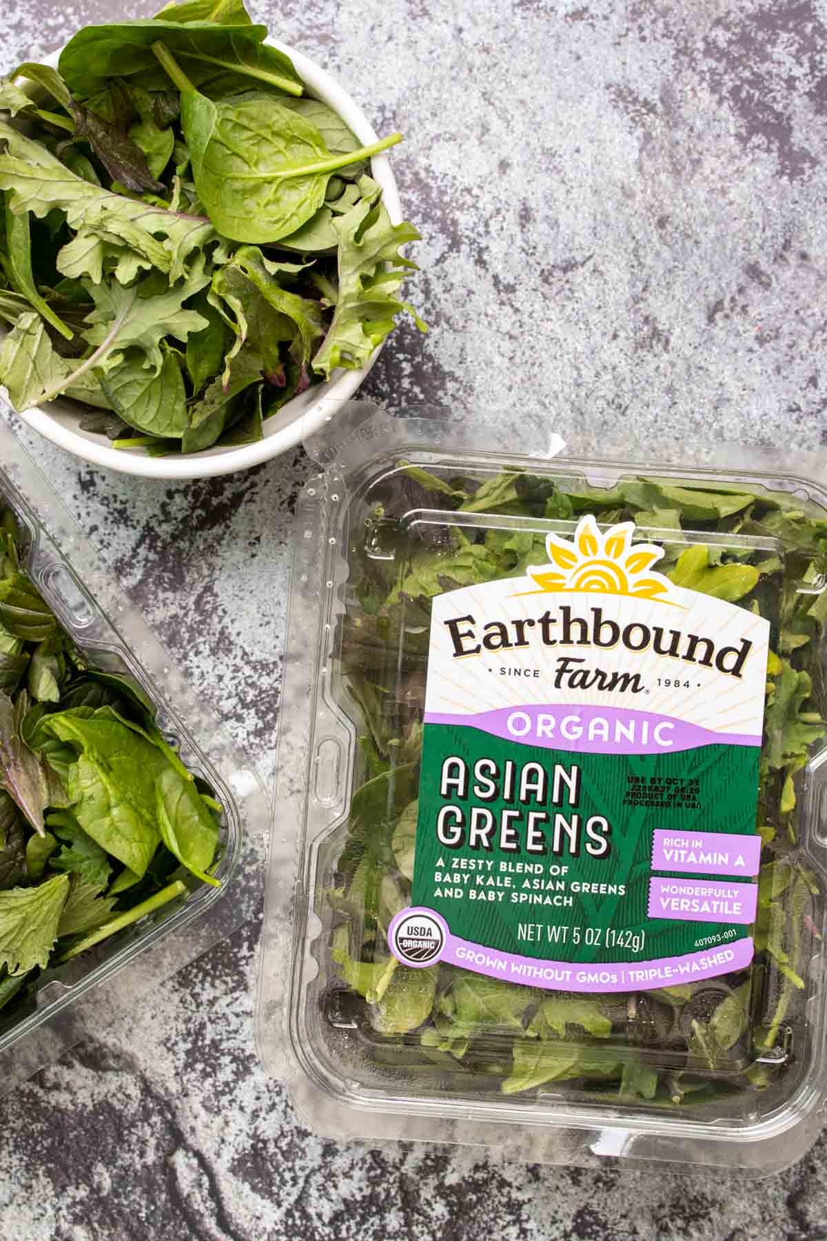 Top view of salad mix container and bowl of greens.