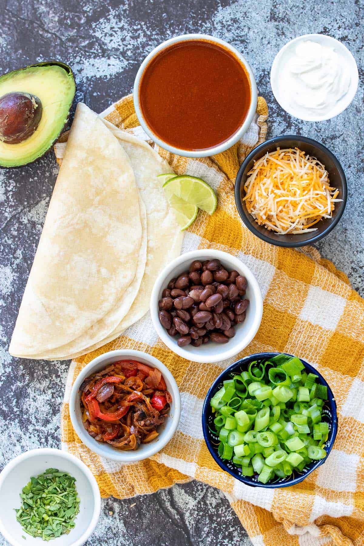 Top view of ingredients in bowls needed to make black bean and veggie enchiladas.