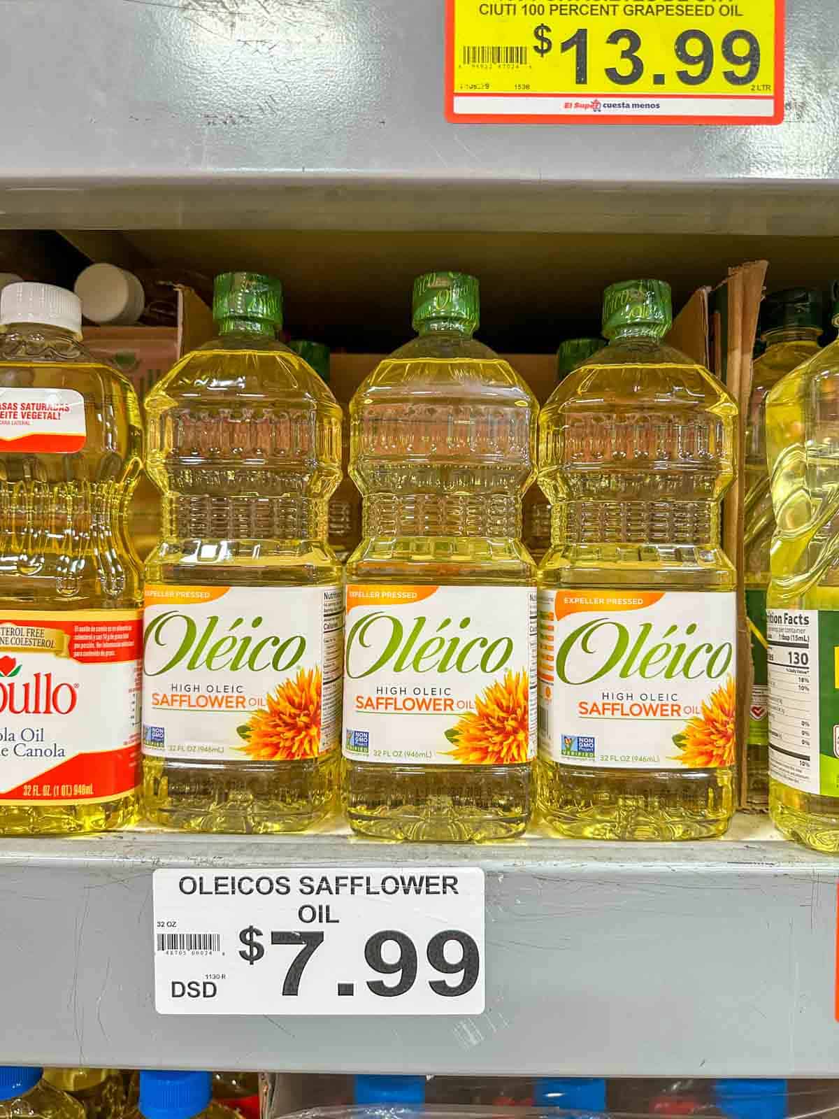 Containers of oil sitting on a store shelf with a price tag under the shelf.