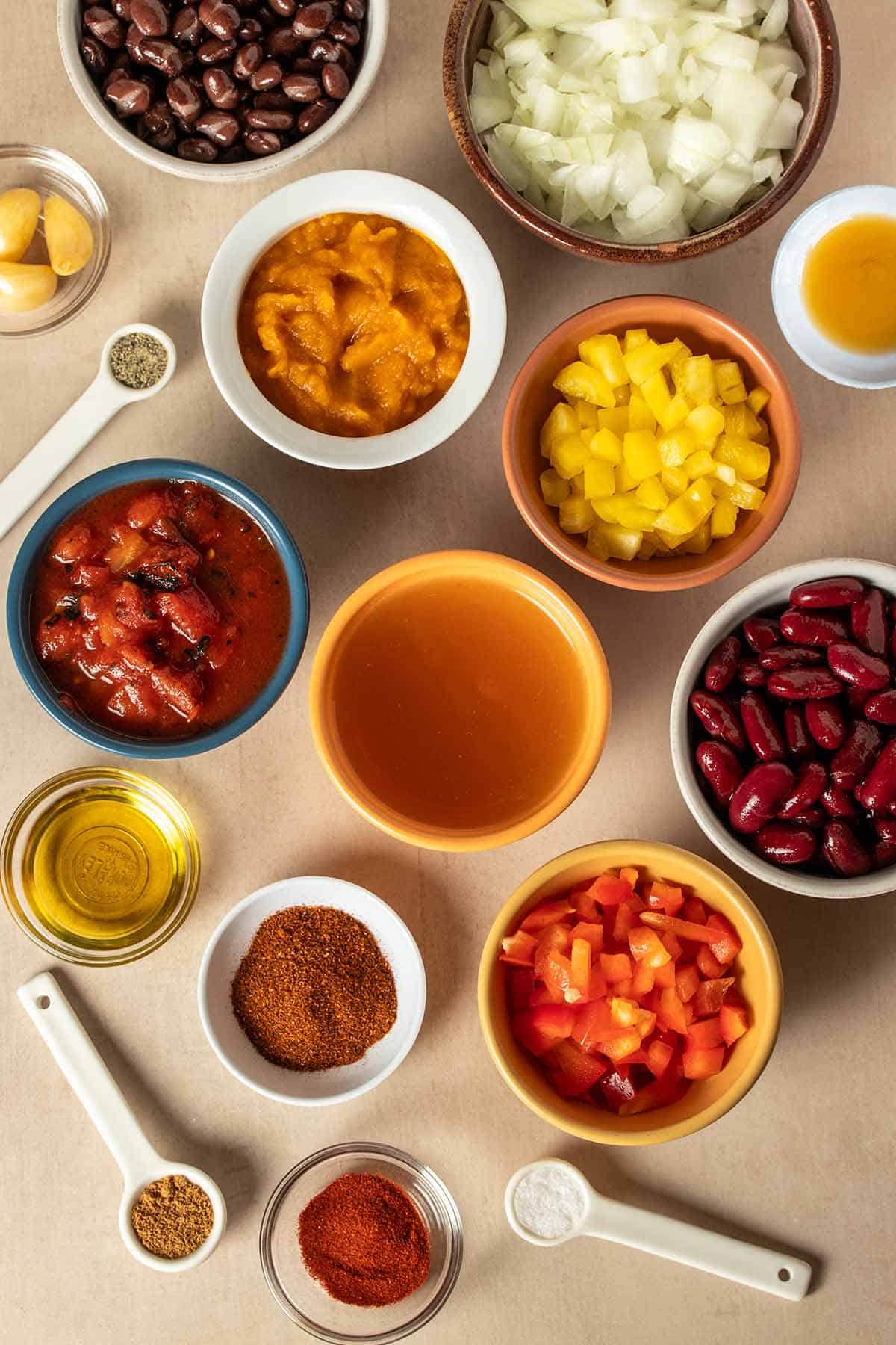 Top view of different bowls and measuring spoons with ingredients needed to make a pumpkin chili.