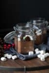 Glass jars with flip lids filled with a hot cocoa mix and mix-ins like marshmallows and peppermint drops.