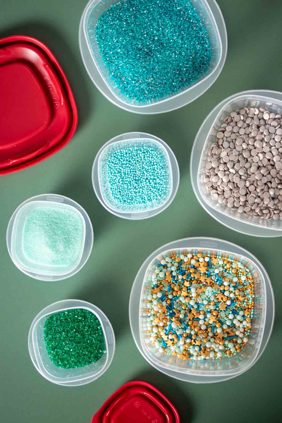 Top view of plastic square containers with different kinds of blue and green sprinkles in them.