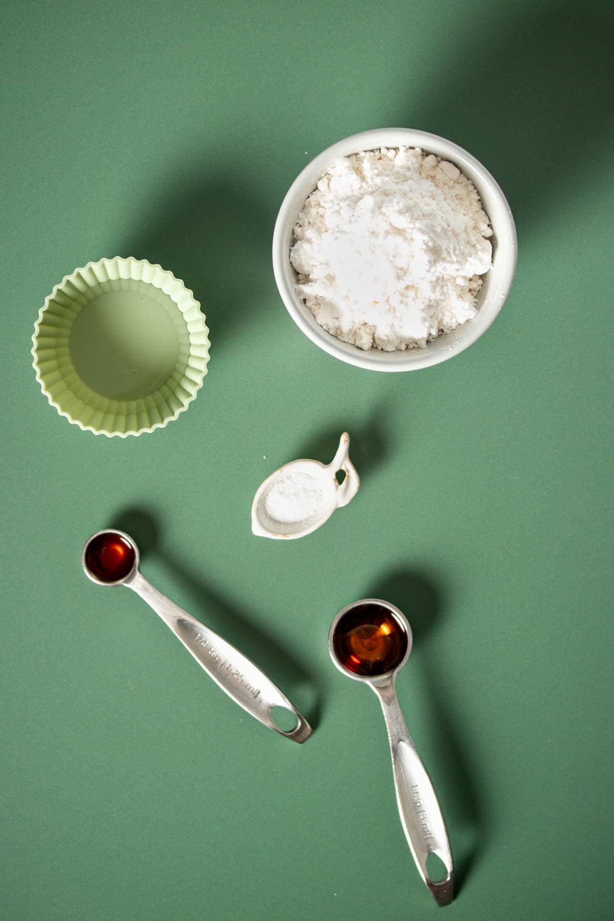 Top view of containers and spoons with ingredients to make a powdered sugar icing.