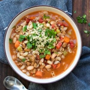 White bowl with pasta and vegetable bean soup inside.