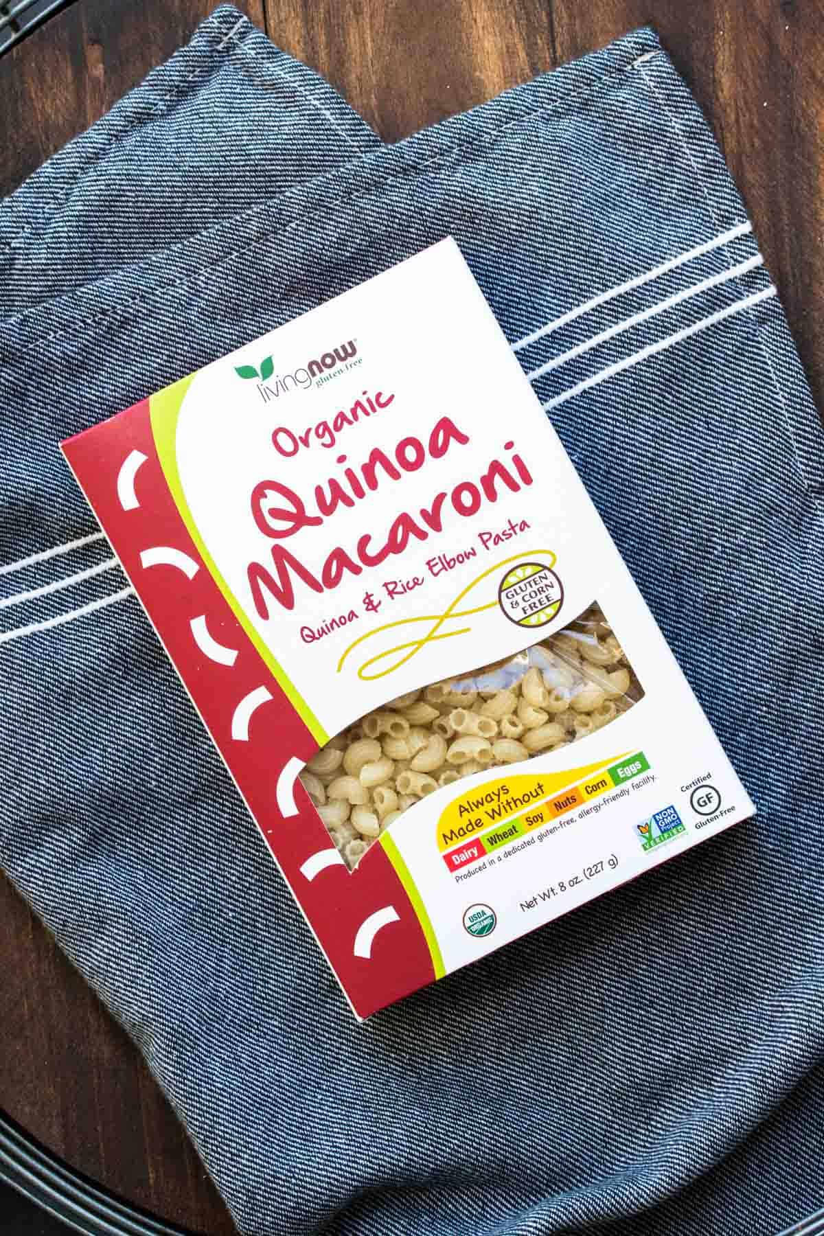 Top view of box of quinoa macaroni pasta on a grey towel.